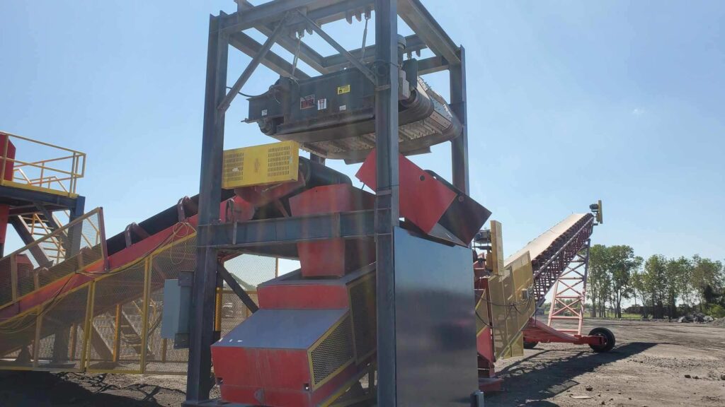 Drum magnet separation structure with discharge chutes and conveyors in a debris processing plant